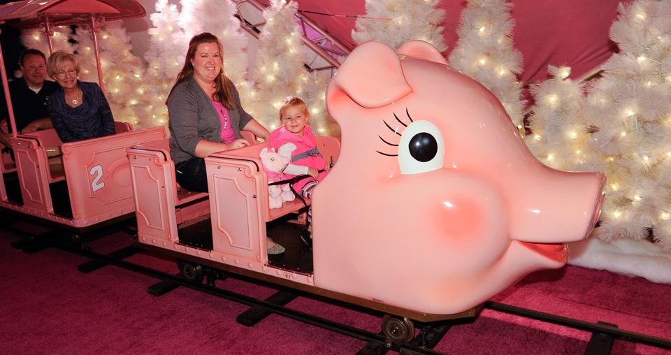 A mother and daughter enjoy a ride on Macys Pink Pig "Priscilla" holiday train 